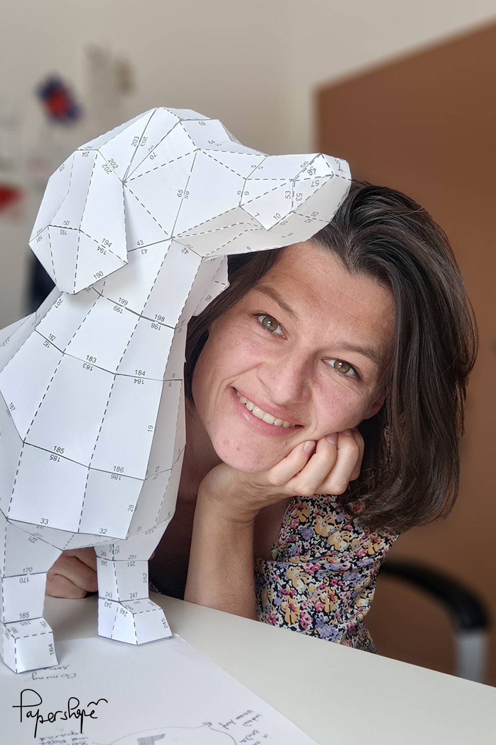 Paper artist with a self-made 3D papercraft dachshund made of copier paper - prototype of the paper model for DIY from Papershape