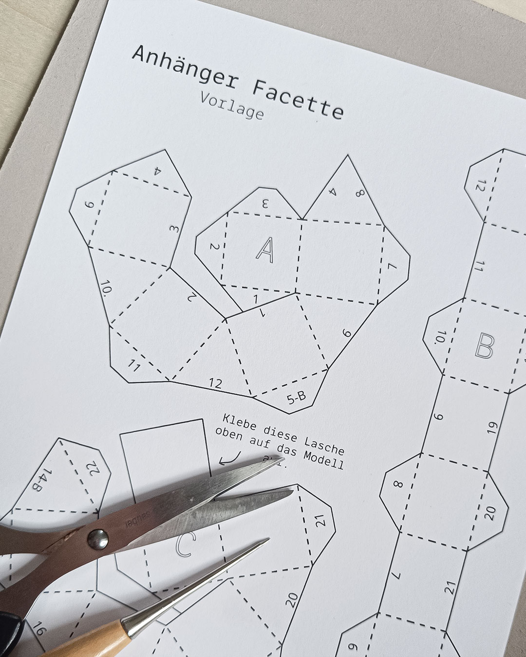 Ausgedruckte Bastelvorlage für einen Papieranhänger mit Schere und Ahle